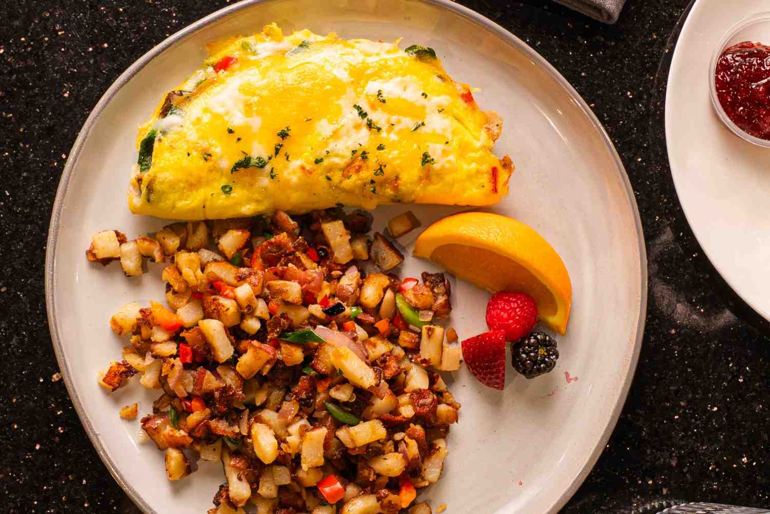 Breakfast omelet with seasoned potatoes, fruit garnish, and jam served at restaurant in Yreka, CA