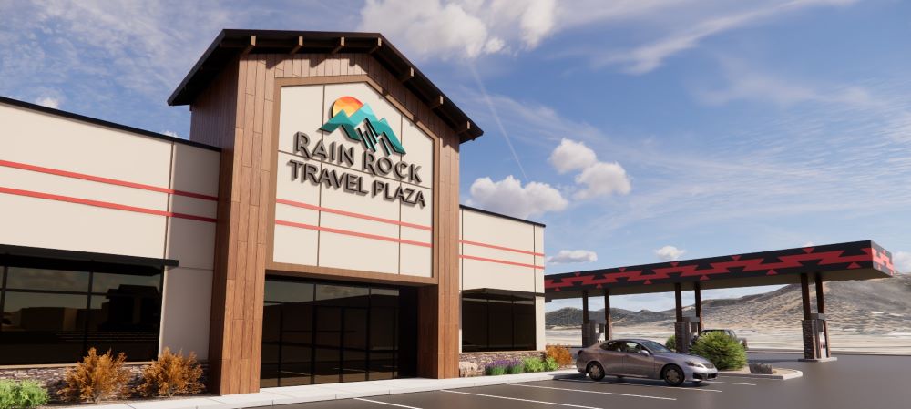Exterior of Rain Rock Travel Plaza with parking area, covered fueling lane, and mountain views

