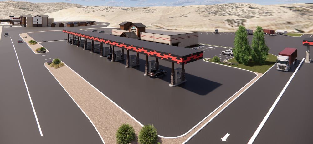 Aerial view of travel plaza with fueling lanes, parking areas, and surrounding hills
